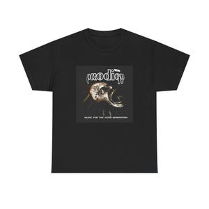 Peut inclure: Un t-shirt noir à manches courtes avec une impression graphique sur la poitrine. L'impression affiche le texte The Prodigy au-dessus d'une illustration de visage criant, avec le texte Music For The Jilted Generation en bas.