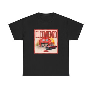 Może przedstawiać: Czarny t-shirt z krótkim rękawem z kwadratowym nadrukiem graficznym na klatce piersiowej. Grafika przedstawia czerwoną stodołę i czerwony pickup z napisem EL COMIENZO dużymi czerwonymi literami nad stodołą oraz małym czerwonym owalem na dole.