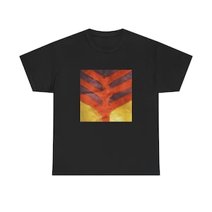 Puede incluir: Una camiseta negra de manga corta con un estampado gráfico cuadrado en el pecho. El diseño muestra una forma central vertical de color naranja similar a una rama, sobre un fondo de rayas horizontales de color morado oscuro y una base amarilla.