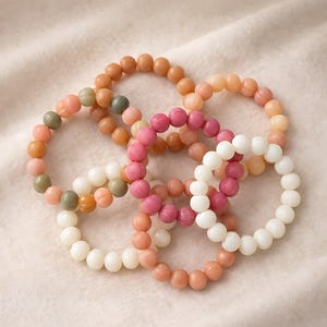 Könnte beinhalten: Ein Set aus drei Keramikbechern mit gesprenkelter, matter Oberfläche. Die Becher sind in Creme-, Hellgrau- und Dunkelgrautönen gehalten. Jeder Becher hat ein schlichtes, minimalistisches Design und einen abgerundeten Henkel.