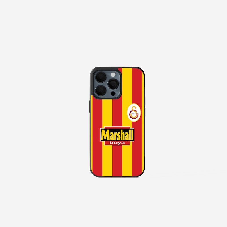 May include: A black phone case with a red and yellow striped design, featuring the text "Marshall boya" in a black rectangle. The case also has a team logo and a black camera module.