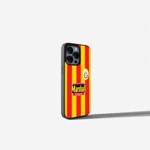 May include: A black phone case with a red and yellow striped design, featuring the text "Marshall boya" and a team logo. The case has a black border and covers the phone's camera.