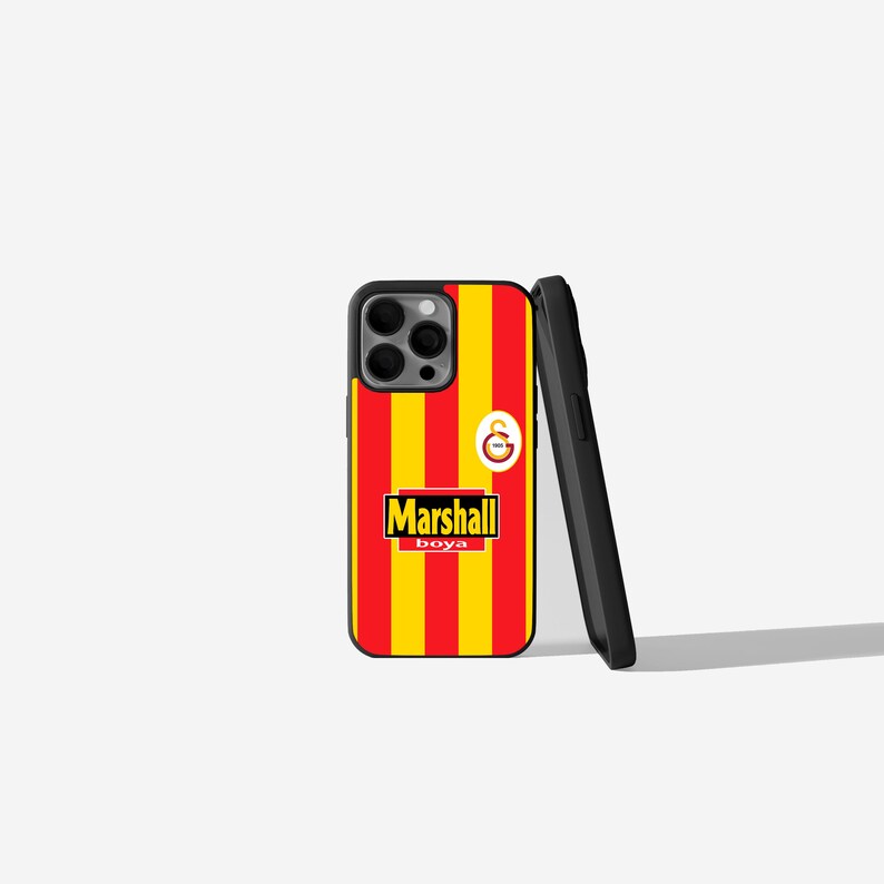 May include: A phone case with a red and yellow striped design, featuring the text "Marshall boya" in a white and yellow box. The case also has a logo with a red and yellow emblem.