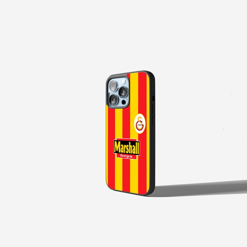 May include: A black phone case with a red and yellow striped design. The case features the text "Marshall boya" in a white font with a yellow outline. A logo is also visible.