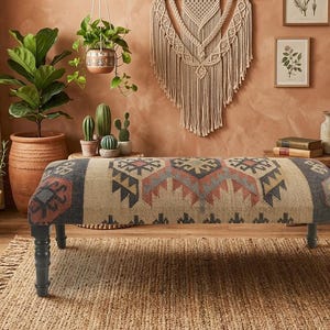 May include: A rectangular upholstered bench featuring a woven fabric top with a multi-colored geometric pattern in shades of red, blue, and beige. The bench is supported by four dark-toned, turned wooden legs with a classic spindle design.