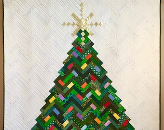 Puede incluir: Una tela acolchada blanca con un diseño de árbol de Navidad de patchwork verde y rojo. El árbol está decorado con una estrella dorada y adornos coloridos.