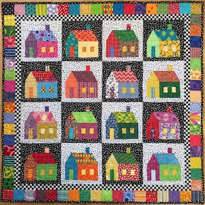 May include: A patchwork quilt with twelve house blocks, each a different colour and pattern, set against a black and white dotted background. The houses have chimneys and windows. The quilt has a black and white checkered border and a patterned edge.
