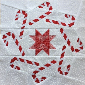 May include: A white fabric with red and white candy cane designs and a red star with a white swirl pattern in the center.