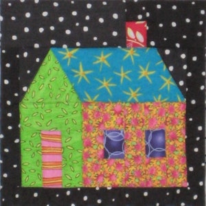 May include: A patchwork house design with a black and white polka dot border. The house has a green side with a door, a floral wall, and a blue roof with yellow star patterns. The chimney is red with a floral pattern.