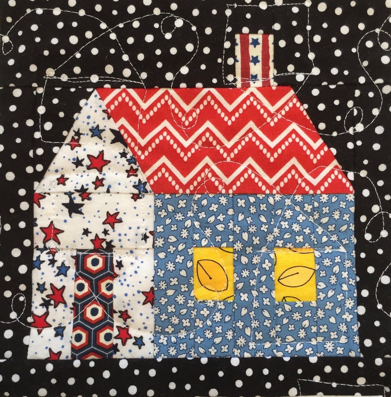 May include: A patchwork house design with a red and white zigzag roof, blue floral walls, and star-patterned sections. The house features yellow leaf-shaped windows and a star-striped chimney. The background is black with white polka dots.