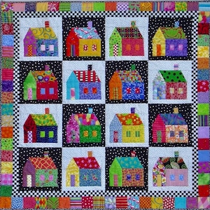 May include: A colorful patchwork quilt featuring a pattern of houses with different colored roofs and windows. The houses are arranged in a grid pattern on a black and white background.