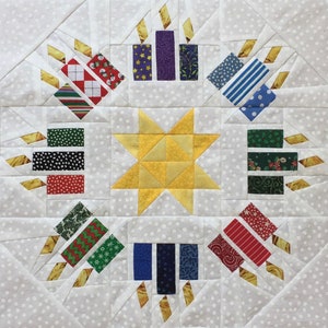 May include: A white quilt block with a yellow star in the centre and eight surrounding blocks featuring candles with various patterned fabrics. The candles are in shades of red, green, blue, purple, and black.