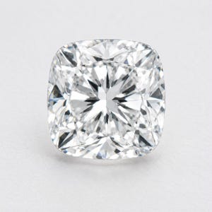 Può includere: Una pietra preziosa incolore a taglio cuscino con una superficie a faccette brillanti. La pietra presenta una forma quadrata con angoli arrotondati e una disposizione simmetrica di faccette triangolari e a forma di aquilone che riflettono la luce.