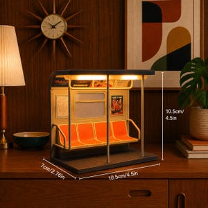 May include: A miniature subway car interior lamp featuring four orange seats, metal poles, and illuminated ceiling lights. The structure measures 4.5 inches in height, 4.5 inches in width, and 2.76 inches in depth, with visible New York signage.