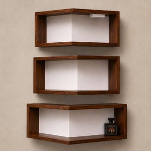 K&ouml;nnte beinhalten: Drei moderne, eckf&ouml;rmige Regale aus dunklem Holz, an einer neutralen Wand montiert. Jedes Regal hat eine wei&szlig;e Innenseite, die einen Kontrast zum Holz bildet. Das untere Regal enth&auml;lt eine kleine, dunkel gef&auml;rbte Flasche.
