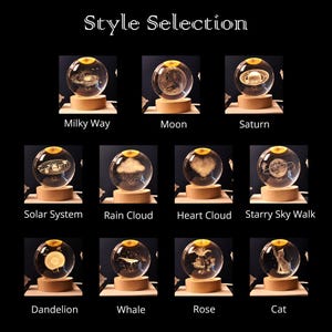 May include: A collection of eleven clear glass spheres with laser-engraved designs including the Milky Way, Moon, Saturn, Solar System, Rain Cloud, Heart Cloud, Starry Sky Walk, Dandelion, Whale, Rose, and Cat, each mounted on a round wooden base.