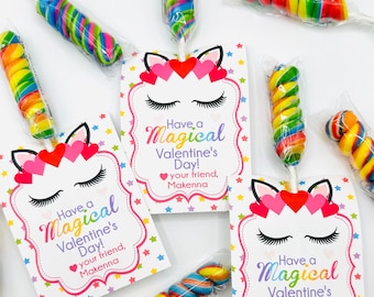 Op de afbeelding: Een set Valentijnsdagkaarten met eenhoorn-thema met een regenboog-spiraalロリポップ bevestigd aan elke kaart. De kaarten hebben een eenhoorn gezicht met wimpers en harten, en de tekst "Have a Magical Valentine's Day! Your friend, Makenna".