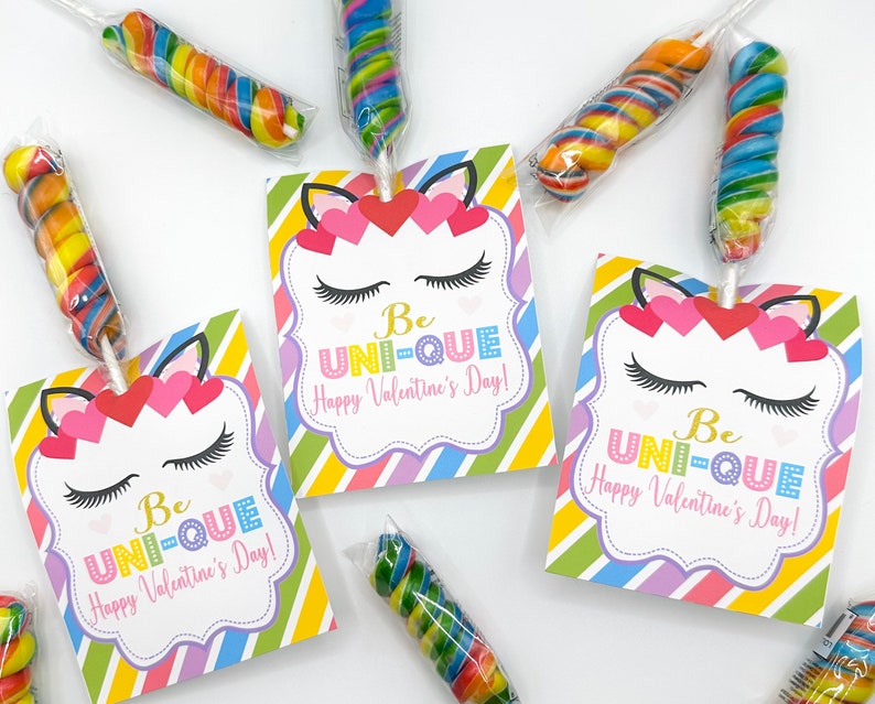 Puede incluir: Tres etiquetas de regalo de San Valent&iacute;n de unicornio coloridas con el texto "Be UNI-QUE Happy Valentine's Day!" Cada etiqueta est&aacute; decorada con una cara de unicornio, pesta&ntilde;as y corazones. Las etiquetas est&aacute;n unidas a piruletas de espiral de colores.