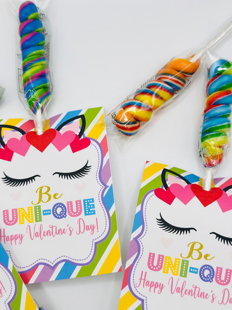 Puede incluir: Un conjunto de dos tarjetas de San Valent&iacute;n con un unicornio con rayas de colores y el texto "Be UNI-QUE Happy Valentine's Day!" Cada tarjeta viene con una piruleta colorida.