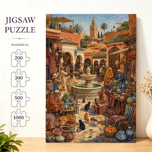 May include: A jigsaw puzzle featuring a vibrant painting of a bustling Moroccan marketplace with a central stone fountain, various vendors, colorful textiles, pottery, and several cats. The text JIGSAW PUZZLE is displayed with options for 200, 300, 500, and 1000 pieces.
