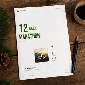 Könnte beinhalten: Ein weißes Dokument mit dem Titel 12 WEEK MARATHON TRAINING PLAN in grüner Schrift, einer zentralen Grafik eines Läufers in einem Sechseck und Statistiken mit 12 Wochen, 5 Tagen pro Woche und 42,2 Kilometern sowie dem Untertitel From 10K to the Finish Line.