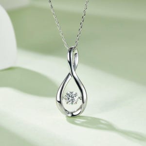May include: A silver pendant necklace featuring a teardrop-shaped design with a sparkling, round-cut gemstone at its center. The pendant hangs from a delicate chain, creating an elegant and timeless piece of jewelry.