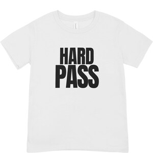 May include: White t-shirt with the words "HARD PASS" printed in bold, black capital letters. The shirt has short sleeves and a crew neck.