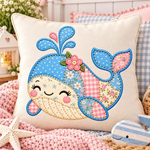 May include: A square throw cushion featuring an embroidered applique of a smiling whale. The whale is crafted from various fabric patches in blue, pink, and white, showcasing polka dot, floral, and gingham patterns with a pink flower on its head.