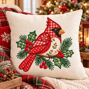 May include: A square off-white throw pillow featuring a central embroidered cardinal bird design. The bird is composed of red and white gingham, polka dot, and floral fabric patterns, perched on a branch with green holly leaves and red berries.