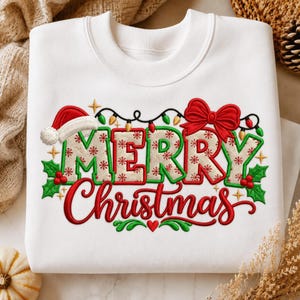 May include: A white crewneck sweatshirt featuring an embroidered design that reads Merry Christmas in red and beige lettering. The text is decorated with a Santa hat, a red bow, green holly leaves, red berries, and colorful string lights.