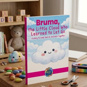 May include: A children's book titled "Bruma, the Little Cloud Who Learned to Let Go" with a smiling cloud illustration. The book is on a wooden table with colorful objects, including a rainbow-colored pencil case and a pair of scissors.