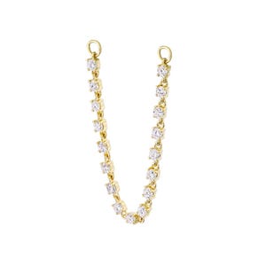 Puede incluir: Una cadena conectora de oro con una serie de pequeñas piedras redondas, transparentes y facetadas, engastadas en biseles de oro individuales. La cadena forma una U y termina en cada extremo con una pequeña anilla de oro para su fijación.