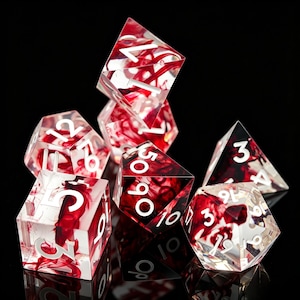 May include: A set of seven polyhedral dice made of clear resin with swirling red ink inclusions. Each die features sharp edges and crisp white engraved numbers. The collection includes a d20, d12, d10, d8, d6, d4, and a percentile die.