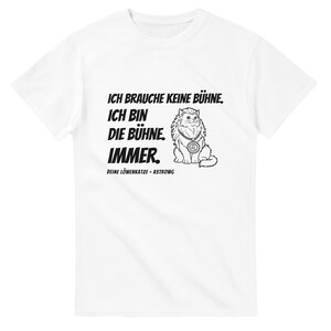 Può includere: Una t-shirt bianca a maniche corte con una grafica nera di un gatto che indossa un medaglione. Il testo recita: ICH BRAUCHE KEINE BÜHNE. ICH BIN DIE BÜHNE. IMMER. DEINE LÖWENKATZE - ASTROWG. Il disegno è centrato sulla parte anteriore del capo.