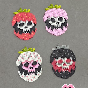 May include: Four colorful skull-shaped bead designs, each resembling a berry. The designs are red, pink, white, and black, with green stems. The text "4 Death Berries" is at the top. The bottom right corner has the text "Puff Bead + Patterns +".