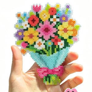 May include: A colorful bouquet of flowers made from fused plastic beads, held in a hand. The flowers include red, pink, yellow, and white blooms, arranged in a blue wrap with a pink bow. The text "Invitation to Bloom" is at the top.