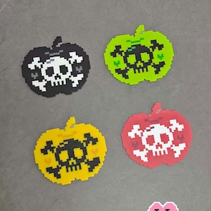 May include: Four pixel art apple-shaped designs in black, green, yellow, and red, each featuring a skull and crossbones. The text "4 Poisoned Apples" is at the top. The bottom right corner has the text "Puff Bead + Patterns+".
