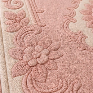 May include: Close-up of a textured, floral-patterned rug in shades of pink and cream. The design features raised, three-dimensional flowers and scrolling details, creating a vintage or retro aesthetic. The rug's surface has a soft, plush appearance.
