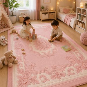 May include: A large, rectangular pink rug with a floral design and a cream-colored border. The rug features a detailed embossed pattern of flowers and scrolling elements. The rug is in a child's bedroom with children playing on it.