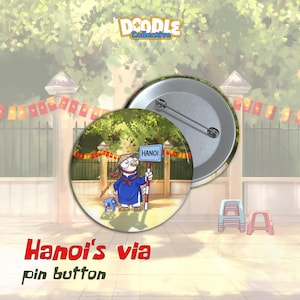 May include: A round pin button featuring a cartoon bird wearing a conical hat and a blue tunic, holding a sign that reads HANOI. The bird stands in front of a fence with red flags. The back of the pin shows a silver metal backing with a pin clasp.