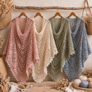 Puede incluir: Cuatro chales triangulares de ganchillo colgados en perchas de madera, con intrincados patrones calados y bordes festoneados. Los chales son de color rosa empolvado, crema, verde salvia y azul pizarra, con una textura detallada de encaje.