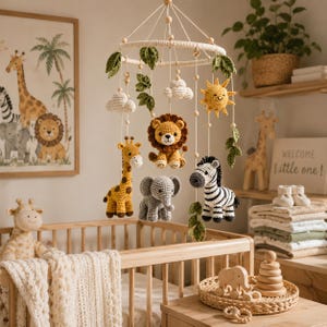 May include: A nursery mobile featuring crocheted figures of a lion, giraffe, elephant, and zebra, accented with a yellow sun, white clouds, and green leaves. The figures hang from a circular frame suspended by strings with small wooden beads.
