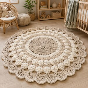 May include: A round, crocheted area rug featuring a concentric pattern of alternating beige and cream yarn. The design includes a solid center, a textured middle section with petal-like stitches, and a scalloped, decorative border edge.