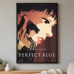 K&ouml;nnte beinhalten: Ein gerahmtes Poster f&uuml;r den Film Perfect Blue von Satoshi Kon. Das Kunstwerk zeigt eine gro&szlig;e Nahaufnahme eines Gesichts in Rot- und Schwarzt&ouml;nen, &uuml;berlagert von einer kleineren Figur mit dunklem Haar, die ein helles Hemd tr&auml;gt.