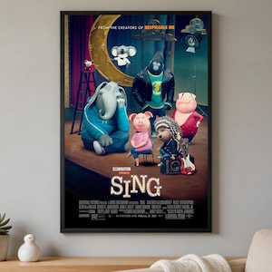 Op de afbeelding: Een ingelijste filmposter voor Sing met geanimeerde personages waaronder een koala, een gorilla, twee varkens, een olifant en een stekelvarken op een podium. De titel Sing staat in grote, verlichte letters in marquee-stijl onderaan in het midden.