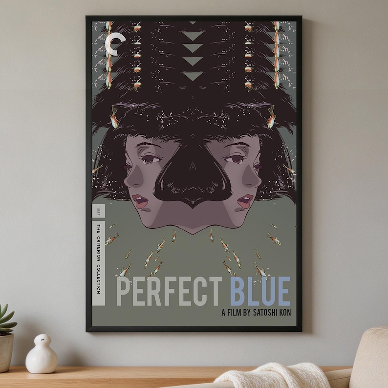 K&ouml;nnte beinhalten: Ein gerahmtes Filmplakat f&uuml;r Perfect Blue, ein Film von Satoshi Kon. Das Kunstwerk zeigt eine gespiegelte Illustration einer Person mit dunklem Haar vor einem grauen Hintergrund, umgeben von kleinen Fischen. Der Text lautet Perfect Blue und The Criterion Collection.