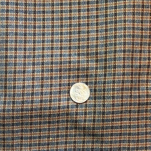 May include: A close-up of a brown, blue, and beige plaid fabric. The fabric has a fine weave and a subtle sheen.