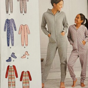May include: A Simplicity sewing pattern featuring various jumpsuit designs. The pattern includes illustrations of jumpsuits in solid gray, floral prints, and holiday-themed patterns. The image also shows two people wearing gray and pink jumpsuits.