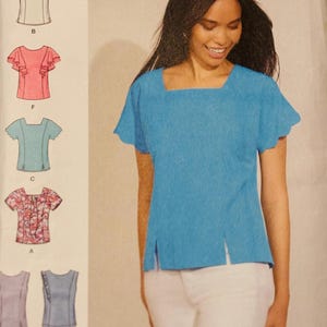 May include: A woman wearing a light blue square-neck top with short sleeves and side slits. The image also shows a sewing pattern with various top designs, including a pink ruffled top and a floral print top.