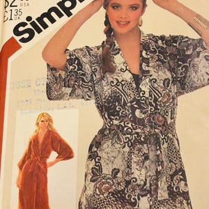 May include: Simplicity sewing pattern featuring a woman wearing a patterned robe with a matching belt. The pattern includes a second image of a long, rust-colored robe. The text "Simplicity" is prominently displayed.